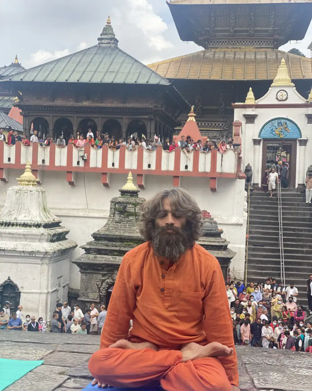 Yogi Ji, Ashok Sharma Bhatta, seated in lotus in saffron dress before the Pashupatinath temple in Kathmandu